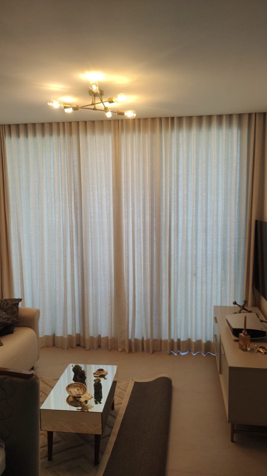 Sala decorada com cortinas bege e iluminação quente